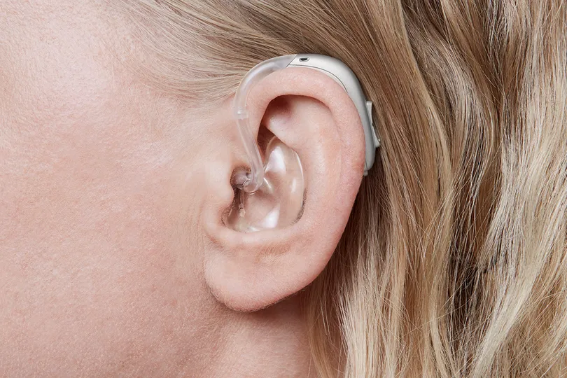 Behind the ear hearing aid shown worn in the ear